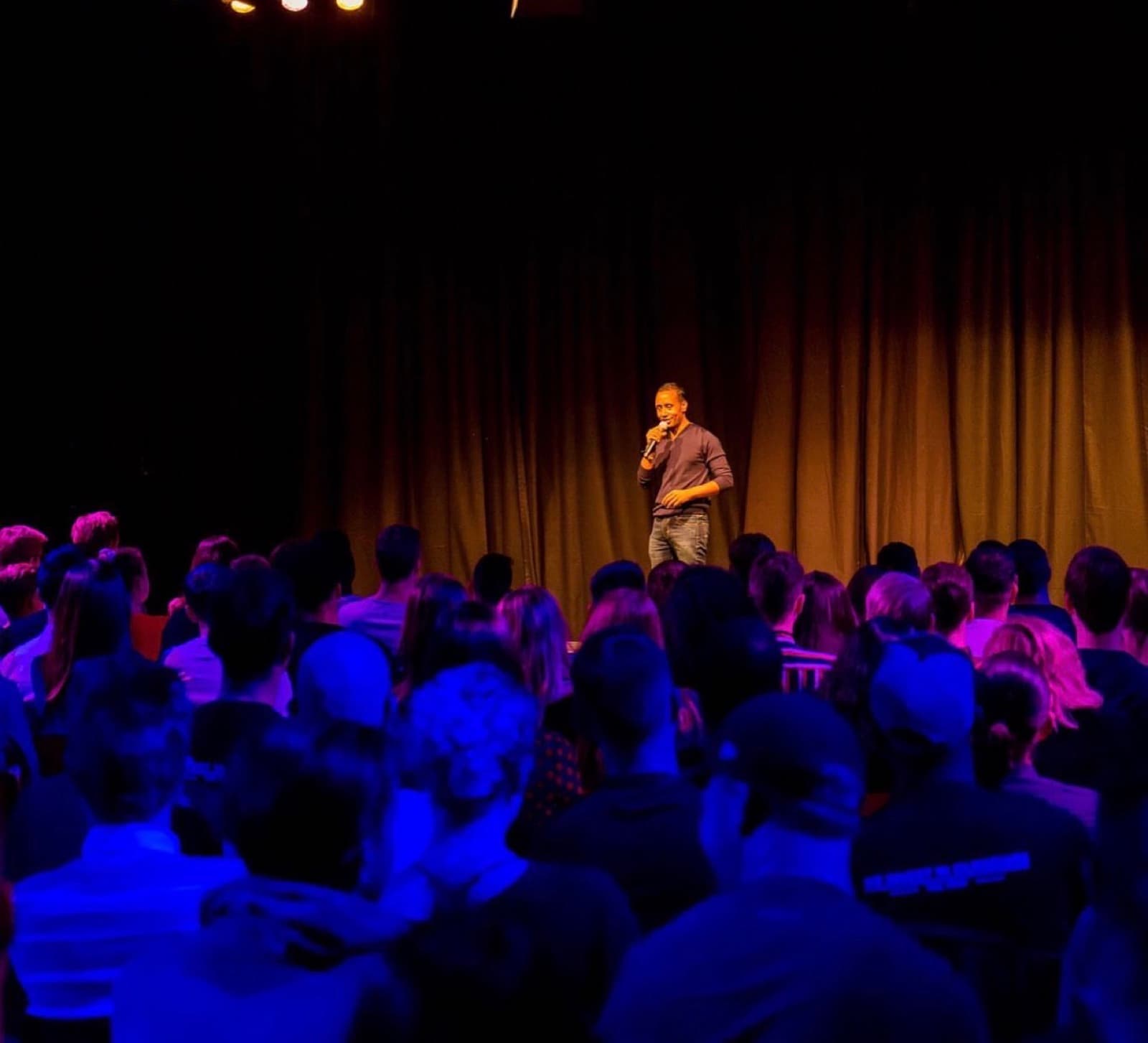 Virgil Brewster speaking on a theatre stage to a seated audience