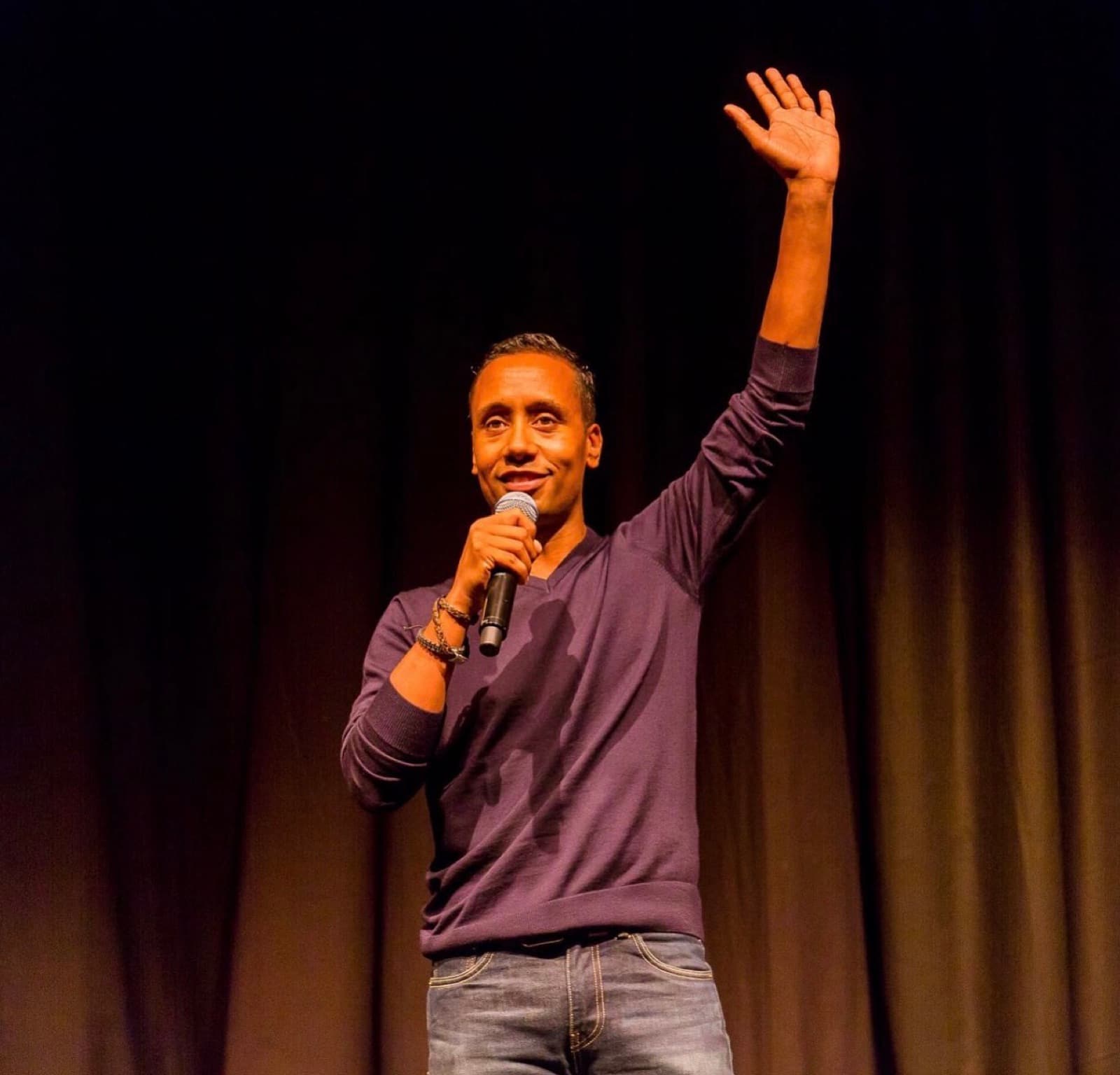 Virgil Brewster on stage with a microphone, one arm raised